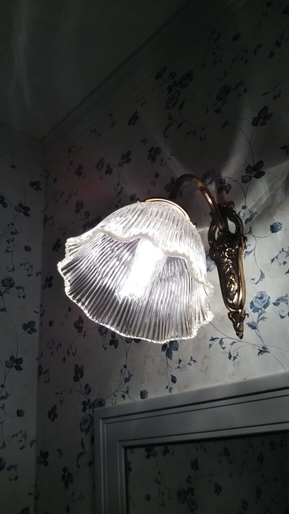 すみれの花が散りばめられたお洒落な壁紙の洗面室の照明－明るいけど落ち着いた光が特徴のブラケットライト　H29邸-1