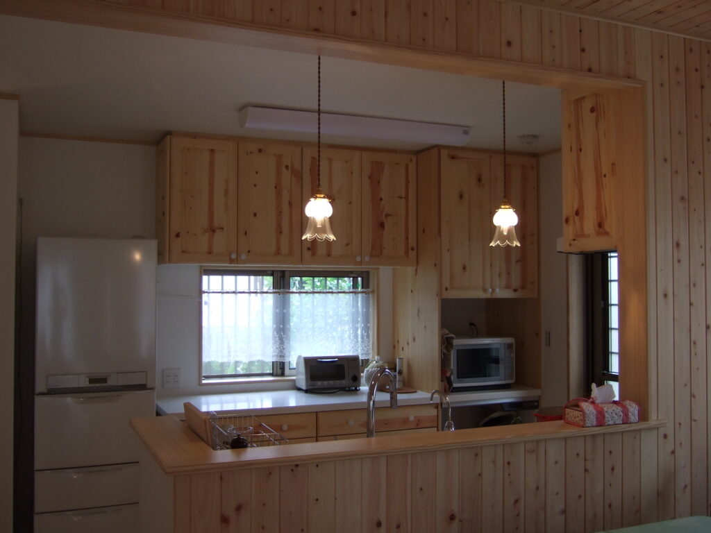 木材をふんだんに使った温かな印象のキッチンにアンティークなペンダントライトが居心地よく納まっています　K09邸