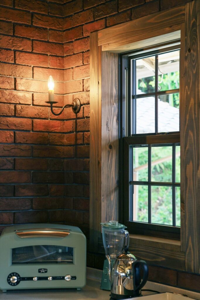古民家リフォームのキッチンで、レンガの壁にアンティーク風なキャンドル型のブラケットライト